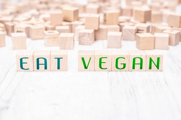 Las palabras comen vegano formado por bloques de madera en una mesa blanca —  Fotos de Stock