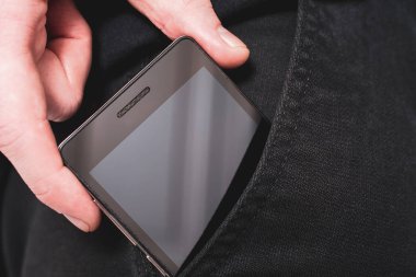 Erkek el kopya alanı bir karanlık pantolon açık cebinden siyah bir Smartphone çekerek