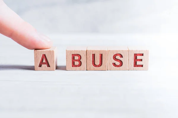 The Word Abuse Formed by Wooden Blocks and Arranged by a Male Finger On A White Table — стоковое фото