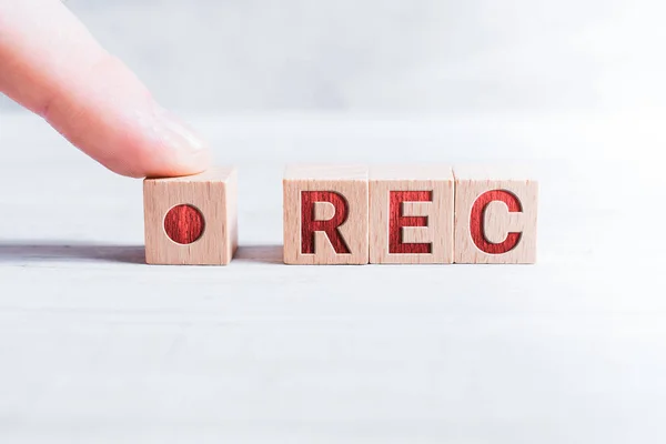 De afkorting Rec gevormd door houten blokken en geregeld door een mannelijke vinger op een witte tafel — Stockfoto