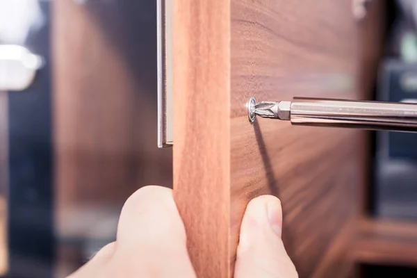 Bir tornavida, DIY kavramı ile kahverengi bir dolap Doorhandle vidayı sıkıştırın — Stok fotoğraf