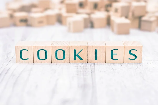 Ordet Cookies bildas av träklossar på ett vitt bord Stockbild