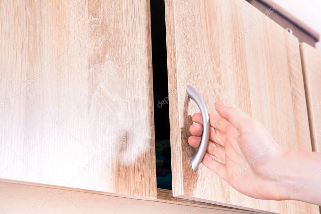 Male Hand Opens The Door Of A Brown Wall Cubboard