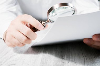 İşadamı bir büyüteç ile onun belgeleri analiz etme