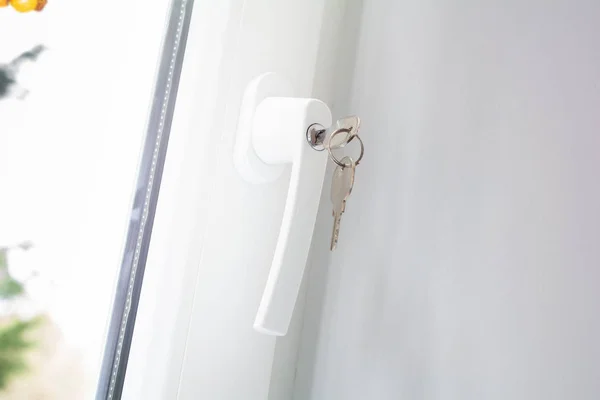 Kilitlenebilir pencere tanıtıcısı ve takılı anahtarları, kapalı bir beyaz pencere önlemek hırsızlık kavramı — Stok fotoğraf
