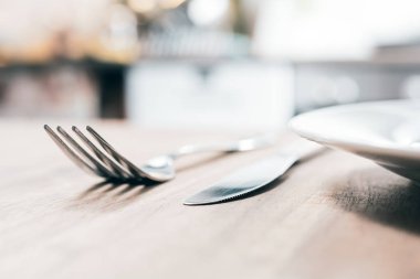 Paslanmaz çatal, bıçak ve seramik plaka ile ahşap bir masa üzerinde bulanık mutfak arka plan