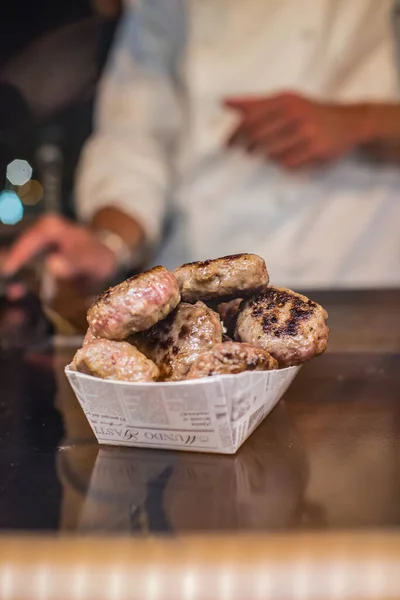 Arka planda aşçı olan bir restoranda küçük hamburger eti sunumu.