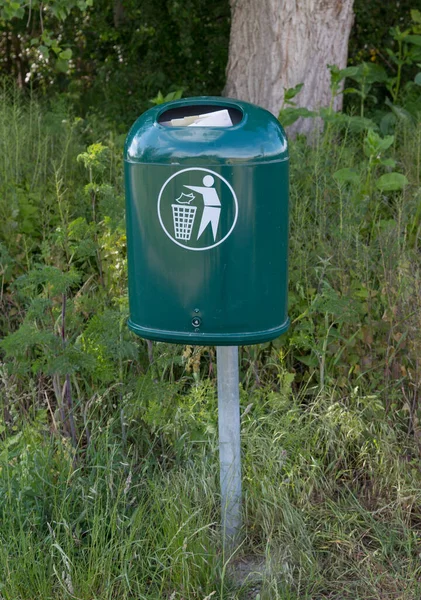 filled green trash can in a landscape