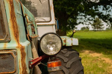 Lambalı, lastikli, yeşil çimenli eski Rus traktörü.