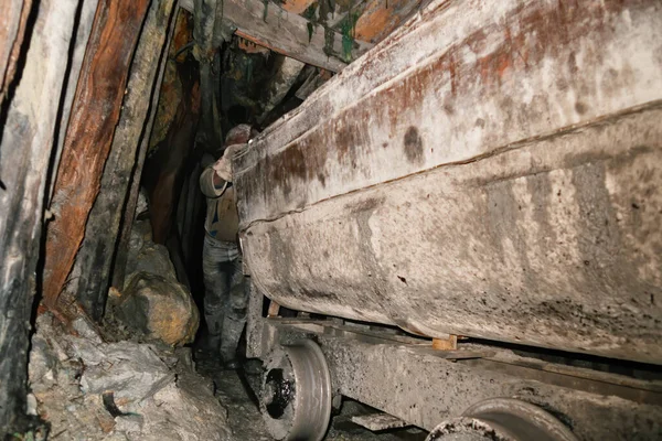鉱山労働者は下から見た銀のトンネルに石でいっぱいの荷車を押しています — ストック写真