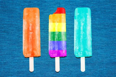 Mavi arka planda turuncu, açık mavi ve gökkuşağı renkleriyle üç dondurma.