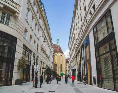 Viyana şehir manzarası ve sokağın ortasında bir kilise. Avusturya 'nın başkentinde şehir merkezinin ünlü simgelerine sahip turistik bir yol. Şehrin tarihi şehir merkezi..