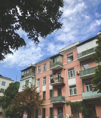 Turuncu renkli ev cephesi, yeşil renkler. Yeşil ağaçlar ve mavi gökyüzü arasında caddede bulunan bina. Avrupa 'nın eski bir kesiminde yaz şehirleri. Ukrayna 'nın Kyiv kentinde turizm kavramı. 