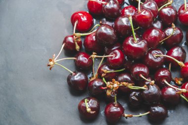 Siyah arka planda vişnelerle resmi kapat. Sol tarafındaki metin için boş alanı olan düz konum. Yaz zamanı ve kırmızı meyveler, duvar kağıdı gibi. Boşluğu kopyala.