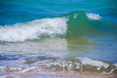 Denizde turkuaz su dalgasının yakın çekimi. Tatilden kalma doğal duvar kağıdı. Denizde suyun arka plan mavisi, dalganın tepesinde küçük beyaz kuzular var. Sahil şeridi için alanı kopyala.