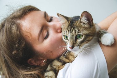 Kız kediye sarılıyor.