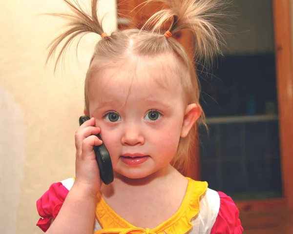 Маленька дівчинка з хвостами поні розмовляє по телефону — стокове фото