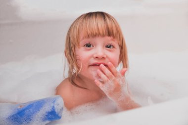Küçük kız banyo köpüğüyle duş alıyor.