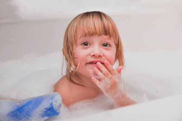 Маленькая девочка принимает душ с пеной для ванны — стоковое фото
