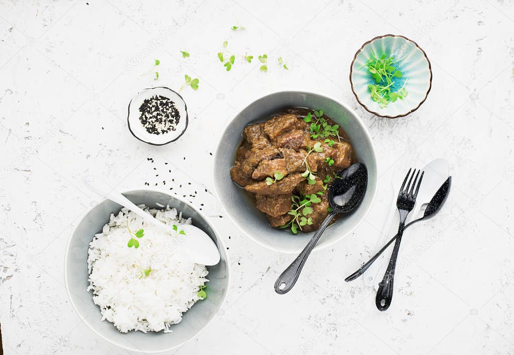 Homemade beef casserole served with rice, with juicy lime and micro greens portioned. Top View.