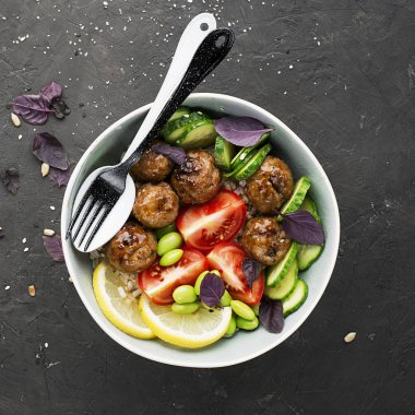 Sağlıklı, dengeli, sağlıklı bir diyet. Köfte, domates, pirinç, salatalık soya fasulye ıspanak limon kase Top görünümü