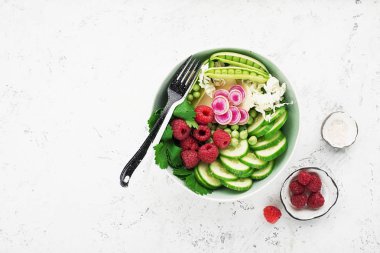 Sebze yaz meyve kase detoks. Vejetaryen Sağlıklı yiyecekler. Salata, marul yaprakları, ahududu, yeşil bezelye, salatalık, havuç, daikon, üst görünüm Yenilebilir çiçekler