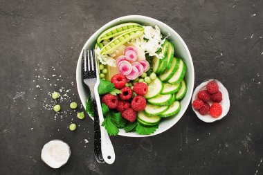 Sebze yaz meyve kase detoks. Vejetaryen Sağlıklı yiyecekler. Salata, marul yaprakları, ahududu, yeşil bezelye, salatalık, havuç, daikon, üst görünüm Yenilebilir çiçekler