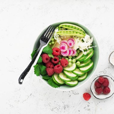 Sebze yaz meyve kase detoks. Vejetaryen Sağlıklı yiyecekler. Salata, marul yaprakları, ahududu, yeşil bezelye, salatalık, havuç, daikon, üst görünüm Yenilebilir çiçekler