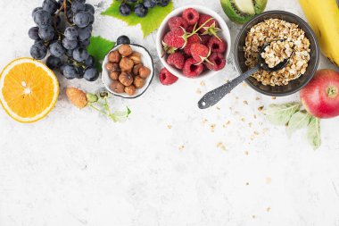 Sağlıklı kahvaltı yemek için malzemeler: ahududu, yaban mersini, fındık, portakal, muz, üzüm mavi, yeşil elma kivi üst görünümü