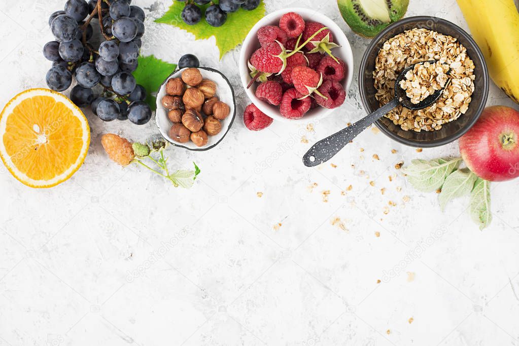 Ingredients for healthy breakfast meals: raspberries, blueberries, nuts, orange, bananas, grapes blue, green apples kiwi Top View