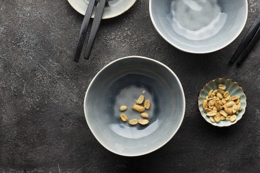 Öğle yemeği servisi için koyu gri arka plan üzerinde plakaları hizmet gri. Çerçeve içinde bir kaç fıstık fındık. Üstten görünüm