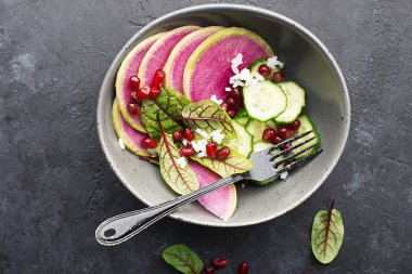 Sağlıklı gıda. Karpuz turp, salatalık, pirinç, nar taneleri, kuzukulağı, Kırmızı damarlar salata bir kase karanlık bir arka plan üzerinde. Üstten görünüm. Kopya alanı.