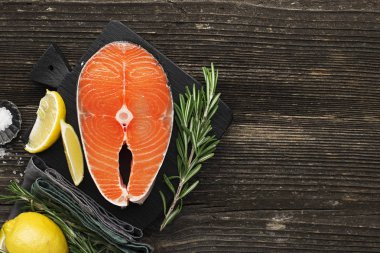 Limon, tuz, bir ahşap zemin üzerine biberiye pişirme önce çiğ biftek somon. Üstten görünüm