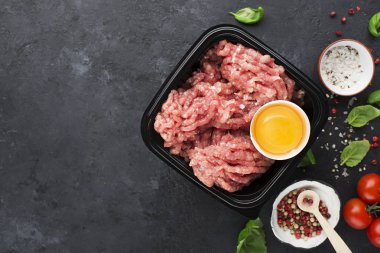 Çiğ kıyma tuz, biber, yumurta, otlar, baharatlar bir burger için. Karanlık bir arka plan üzerinde. Üstten görünüm.