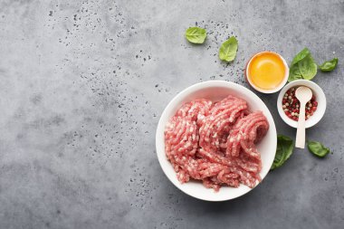 Taze kıyılmış domuz ile yumurta, tuz, biber, domates fesleğen yaprakları ile hafif bir arka plan üzerinde pembe. Üstten görünüm.