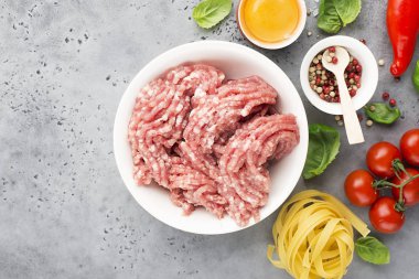 Taze kıyılmış domuz ile yumurta, tuz, biber, domates fesleğen yaprakları ile hafif bir arka plan üzerinde pembe. Üstten görünüm.