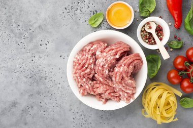 Taze kıyılmış domuz ile yumurta, tuz, biber, domates fesleğen yaprakları ile hafif bir arka plan üzerinde pembe. Üstten görünüm.