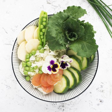 Güzel vitamini sağlıklı sebze salatası. Salatalık, lahana, daikon, marul, aynı kapta genç bezelye. Üstten görünüm.