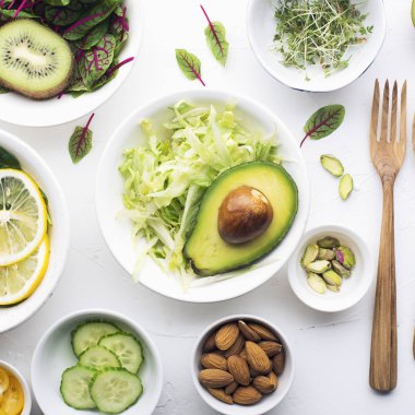 Bahar için yeşil malzemeler detoks salata: ıspanak, Kırmızı damarlar, salatalık, turp, marul, yeşil bezelye, avokado, limon, microgreen, beyaz bir zemin üzerine sarı domates ile kuzukulağı