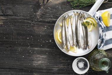 Deniz ürünleri. Küçük deniz küçük balık kokuyor, hamsi, sardalya yağ, tuz ve limon ile pişirme için formunda. Uzay kopyalayın. Üstten görünüm.