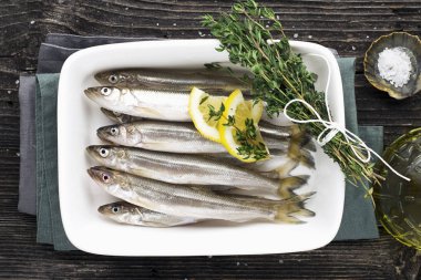 Yararlı küçük deniz balık. Yem, sardalya, hamsi yemek tuz, limon, tereyağı, bir ahşap zemin üzerine kekik ile daha önce. Üstten görünüm.