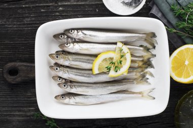 Taze deniz küçük soğuk su balıkları yiyerek arıtmak, sardalya, hamsi doğru sağlıklı doğal beslenme kavramı için limon dilimleri ile basit bir arka plan üzerinde gibi. Üstten görünüm.