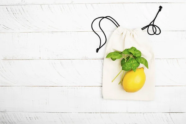 Citron och basilika på vit bomull eco bag på vit trä bakgrund. Begreppet ingen plast noll avfall hus shopping. Kopiera utrymme. Ovanifrån. — Stockfoto