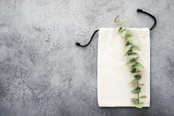 Eucalyptus branch on eco cotton bag for shopping and for items on a light background. Top view. Copy space — Stock Photo, Image