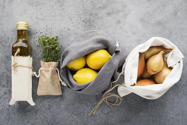 Zero waste house kitchen. Lemons, shallot onions, olive oil, thyme in cotton reusable bag bags. Top view.