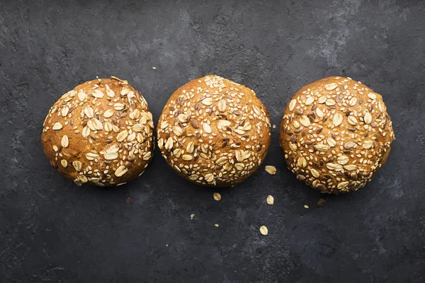 Petits pains de hamburger à grains entiers sur fond sombre. Vue de dessus, espace . — Photo