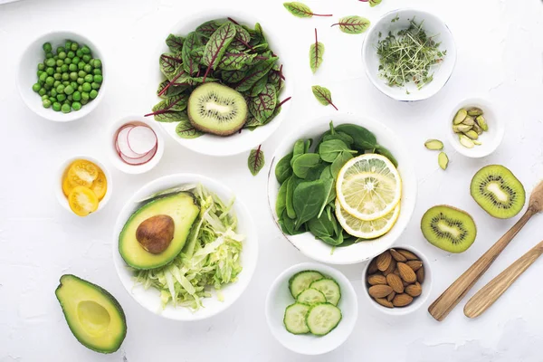 Groene ingrediënten voor lente detox salades: spinazie, zuring met rode aderen, komkommer, radijs, ijsbergsla, groene erwten, avocado's, citroen, microgreen, gele tomaten op een witte achtergrond met — Stockfoto