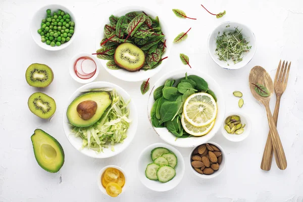Зеленые ингредиенты для весенней детоксикации салатов: шпинат, соррель с красными венами, огурцы, редис, салат айсберг, зеленый горох, авокадо, лимон, микрозеленый, желтый помидор на белом фоне с — стоковое фото