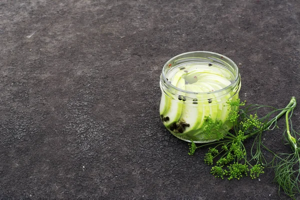 Conservación. Trozos de calabacín salados marinados en un frasco con especias y hierbas en el jardín sobre la mesa. Enfoque selectivo . Fotos De Stock
