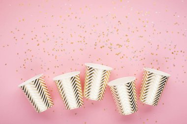 Konfeti, kağıt moda bardak narin pembe bir arka plan üzerinde evrensel popüler festival arka plan pembe altın. Kavram herhangi parlak proje eğlenceli. Yatay, kopya alanı,